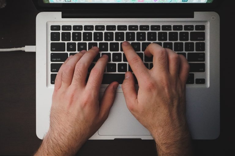 Close up of a man's hands typing on a laptop