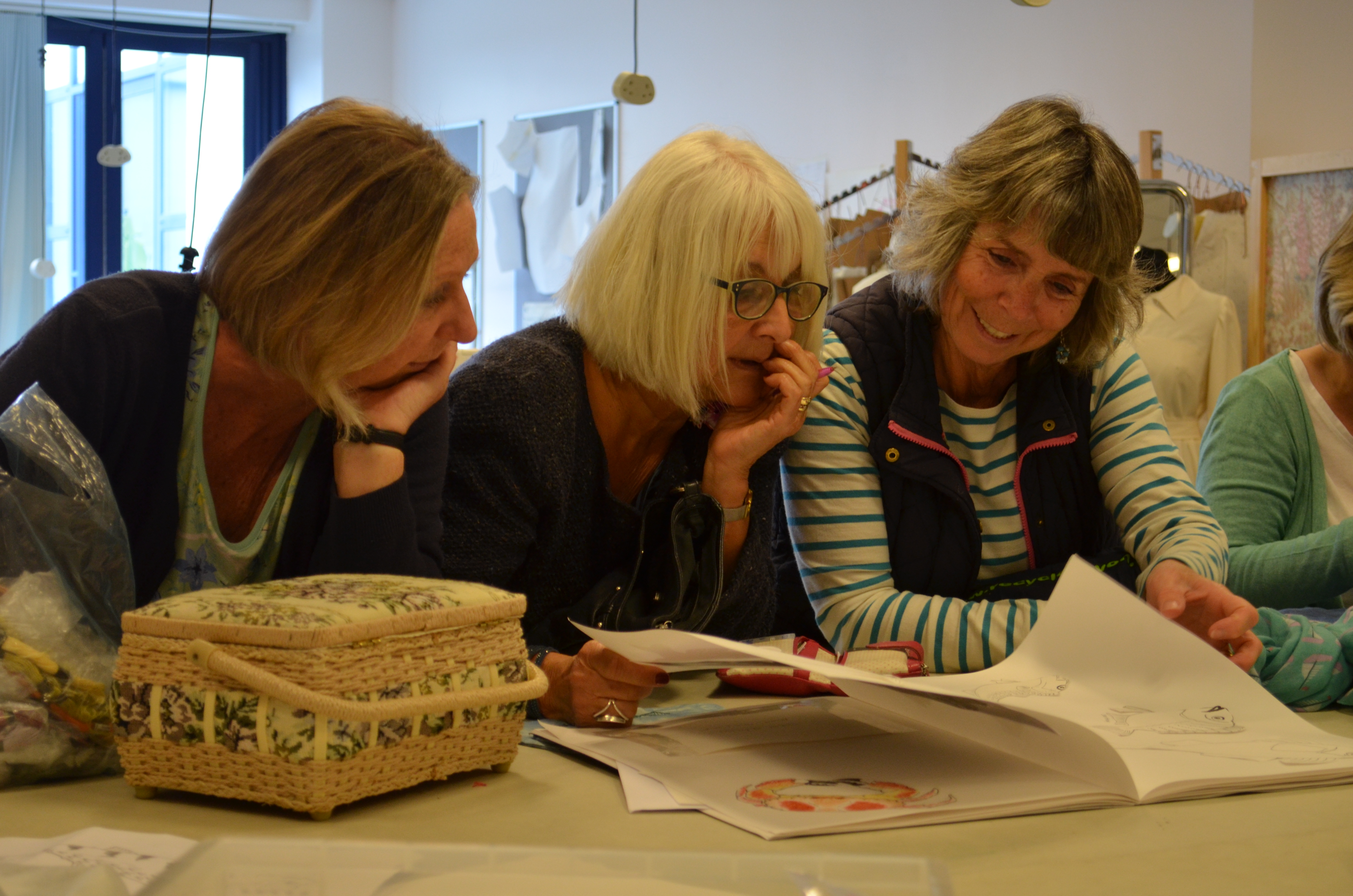 Three people looking at design book preparing for museum fish hawker exhibition.