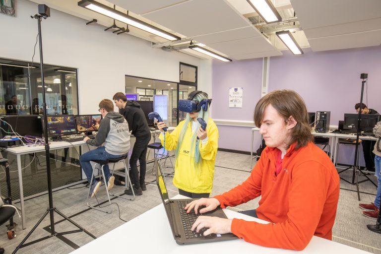 Students using laptops, computers and a VR headset