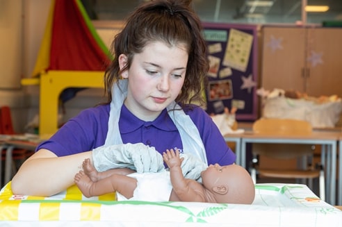 Childcare student changing a baby's nappy