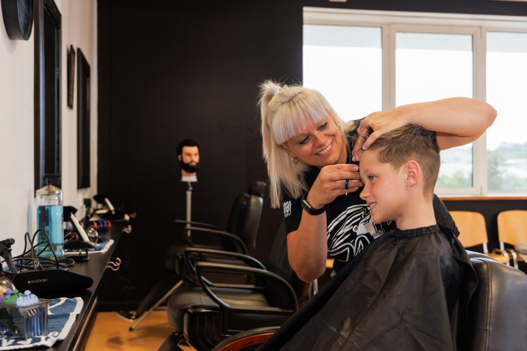 Barbering student cutting boys hair